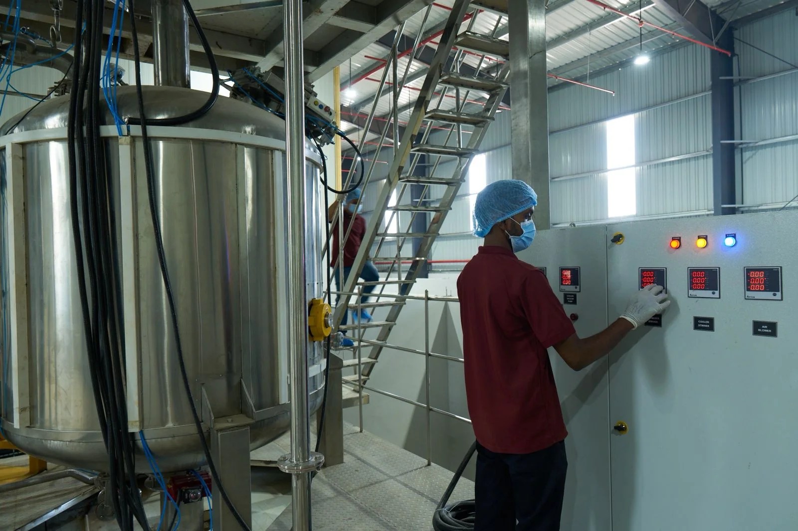 Operator setting parameters on a control panel beside a jacketed process vessel